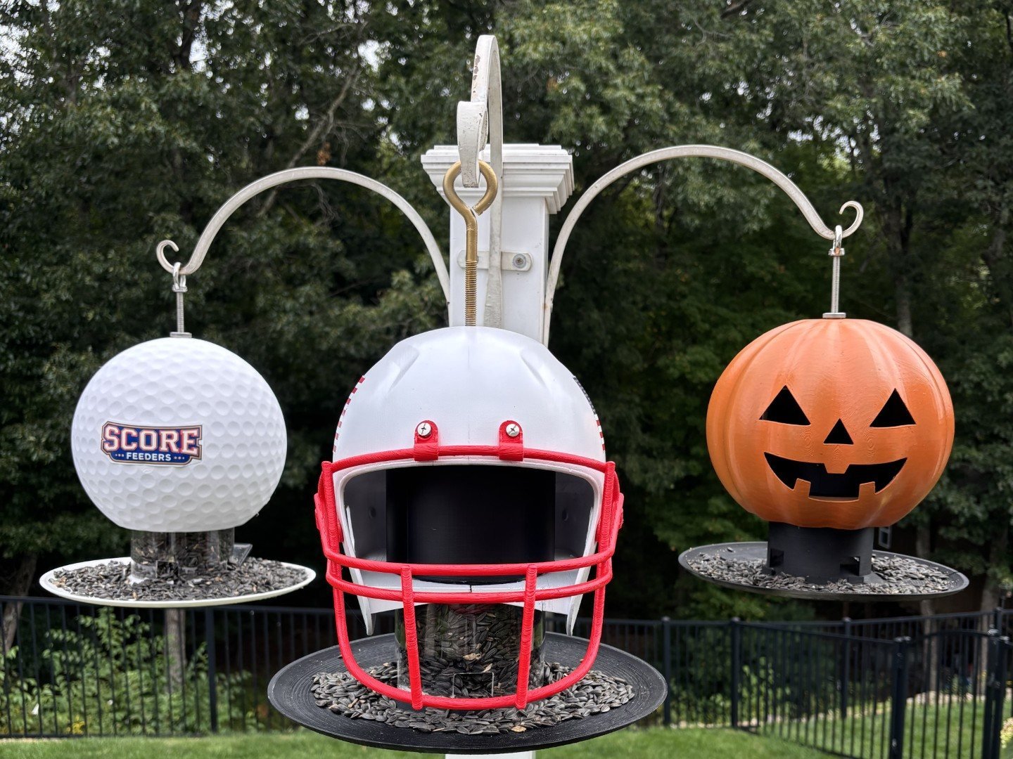 The Eagle golf ball, Stars and Stripes football helmet inspired feeder and Jack jack-o-lantern ScoreFeeders hanging on one garden pole